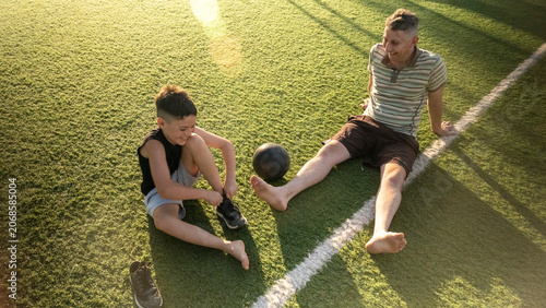 Dad and son preparing to play soccer on synthetic turf field during late afternoon hours in a casual setting