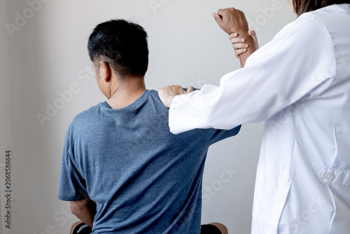 Female doctor hand rehab physical therapy by extending the pain shoulder of a patient. treatment with stretch exercises