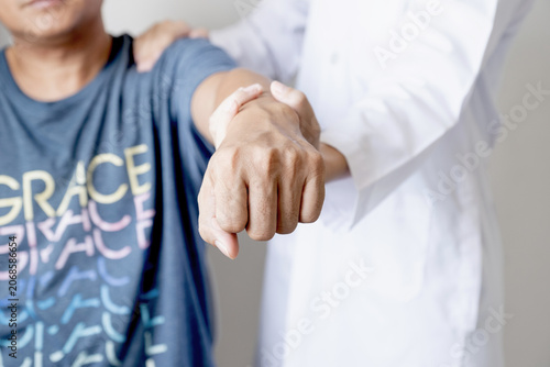 Female doctor hand rehab physical therapy by extending the pain shoulder of a patient. treatment with stretch exercises