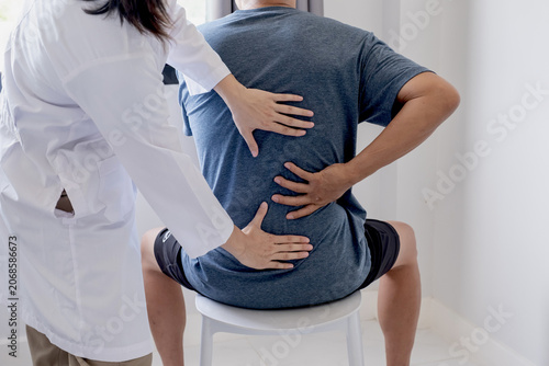 Female doctor hands doing physical therapy By extending the back of a male patient