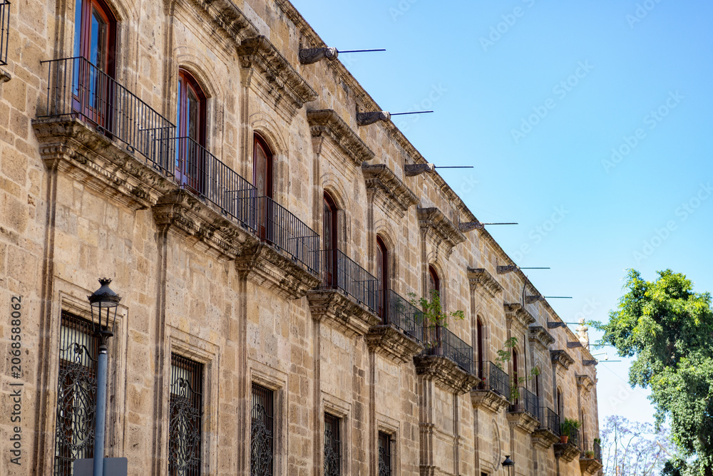 Fototapeta premium Historic Colonial Stone Building with Balconies and Ornate Facade Under Blue Sky