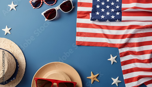 Sunglasses and straw hats lay on a blue surface next to folded American flag fabric and star shapes.