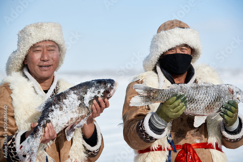 Fotografía People ice-fishing on the frozen lake during the cold winter.