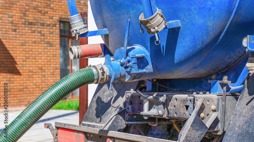 Foto Septic tank service truck connects to suction line for waste removal at a reside
