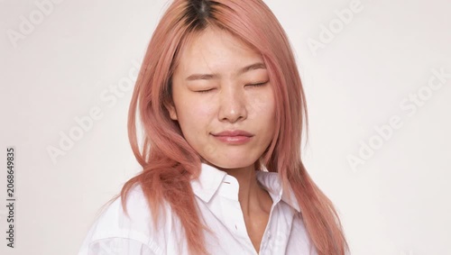 Real East Asian woman with pink blonde hair touches neck in beauty studio portrait