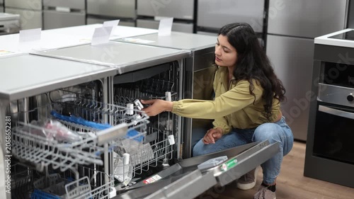 Woman is shopping in a store - choosing a new dishwasher. High quality 4k footage