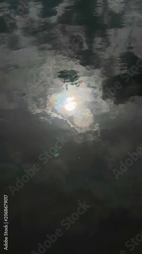 Bright light shimmering on dark rippling water at nighttime