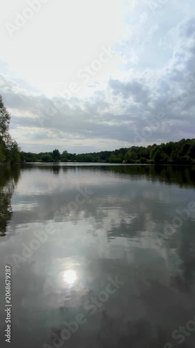 Calm lake surface mirroring dramatic clouds and lush forest