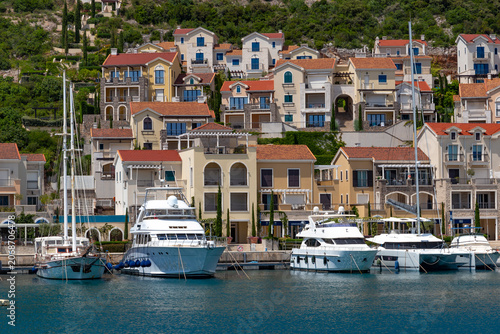 Elegant luxury yachts moored at the pier against the backdrop of upscale premium apartments in the exclusive Lustica Bay resort, Montenegro