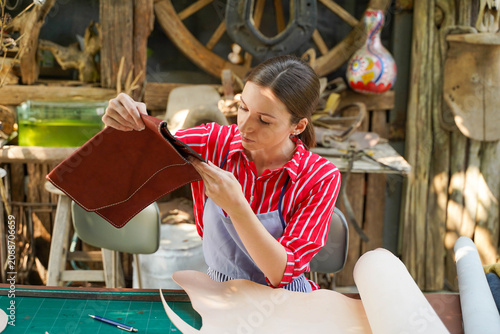 Принти на полотні Young female leather goods maker looking and check the neatness of the leathers bag before sell to customer in workshop