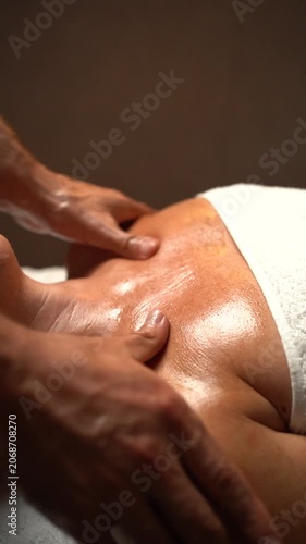 Close-up of male hands providing a deep tissue massage on an oily back in a relaxing spa setting
