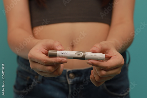 Konstfotografi GLP 1 injection pen held by woman for medical weight management, focus on hands