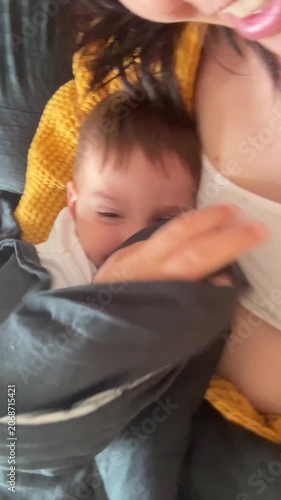 Mother cuddling sleeping baby in bed at home