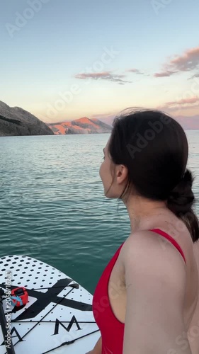 Woman on paddleboard at calm lake sunset