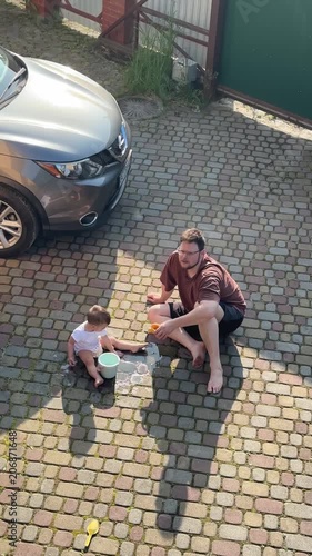 Father and child playing on a cobblestone driveway