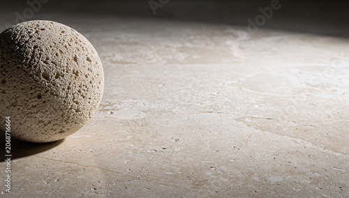 Close up of porous beige pumice stone sphere on polished travertine surface background