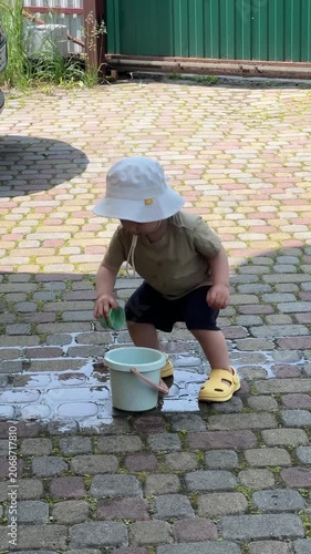 Toddler playing with water on a cobblestone patio