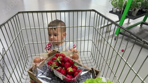 Baby in shopping cart with fresh strawberries