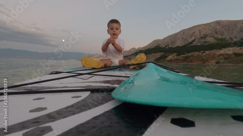 Child on paddleboard at dusk by the sea