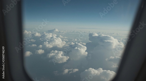 Breathtaking Passenger POV from an Airplane Window Overlooking Dense Fluffy Clouds and Clear Blue Sky