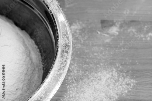 Flour in bowl on wooden table background. Black and white image