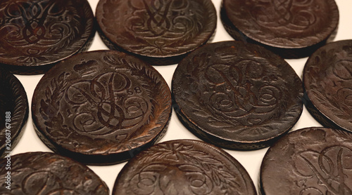 Close-up of old dark brown 5 kopeck coins Elizabeth Petrovna 1758-1762 spread on a light background, showing worn engraved details and antique texture. Ideal for history, money, collecting.