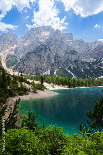 Obraz na płótnie Turquoise water of Lake Braies with gravel shore surrounded by green pine forest