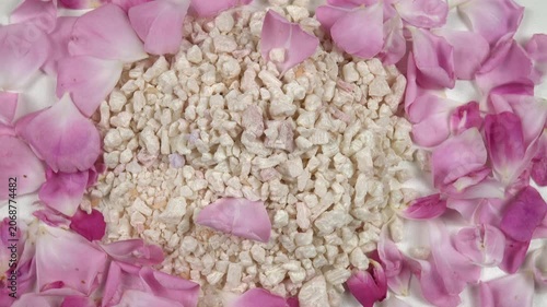Heap of relaxing rose bath salt with use rose essential oil, fresh pink rose petals are on a white table, background, top view