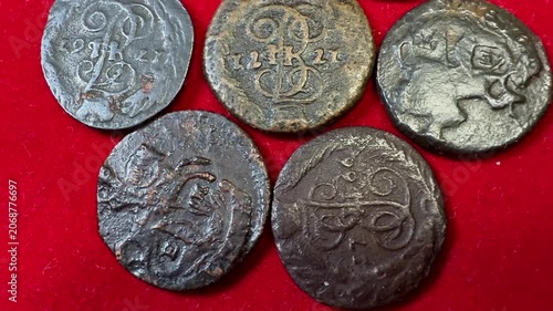 Close view of old worn Polushka coins 1766-1796 Russian Empire Catherine II on red fabric, showing aged metal texture, engraved symbols and a vintage collectible look.