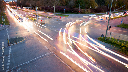 Autos fahren in der Dämmerung mit Licht über die Kreuzung einer vierspurige Straße