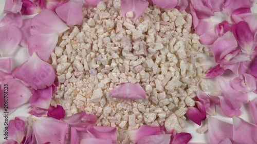 Heap of relaxing rose bath salt with use rose essential oil, fresh pink rose petals are on a white table, background, top view