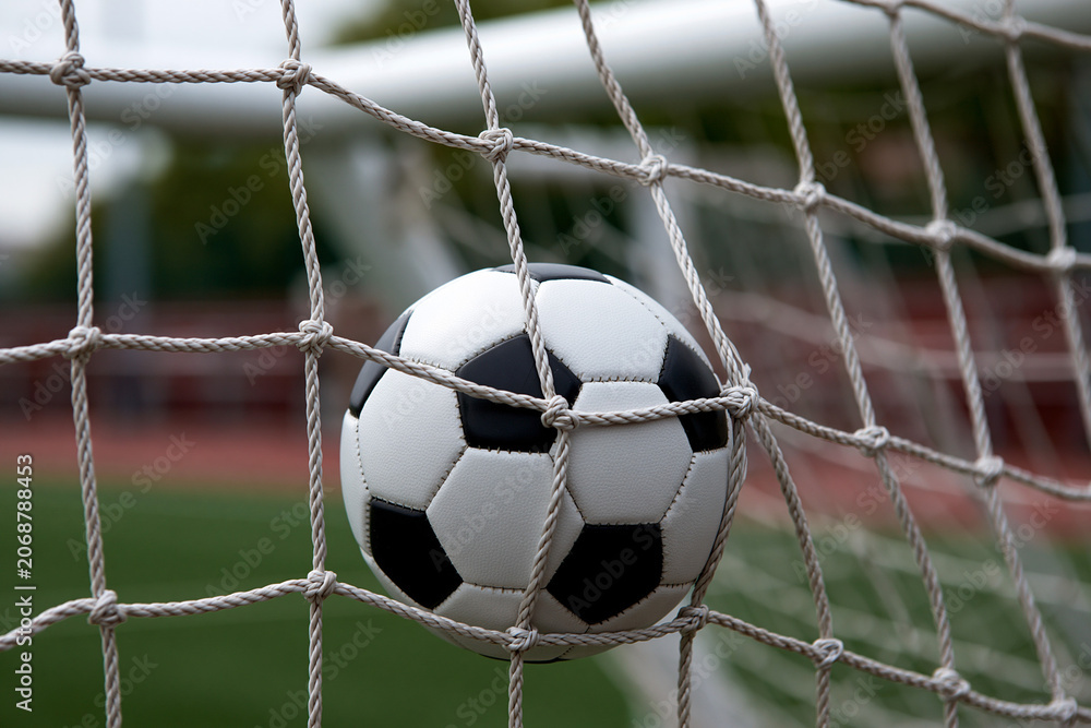 Naklejka premium Soccer ball caught in goal net during a match