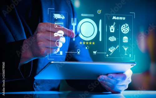 Close-up of a person using a tablet with glowing digital food delivery and restaurant menu interface.