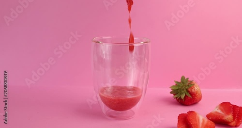 Pouring homemade strawberry puree into empty glass for healthy kid friendly recipe. Child nutrition concept focuses on natural organic vitamins without additives or artificial colors. Minimalist