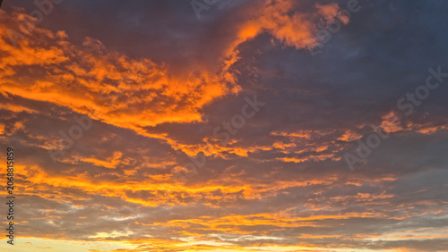 Cuadro en lienzo Orange and grey clouds illuminated by sunset light across evening sky