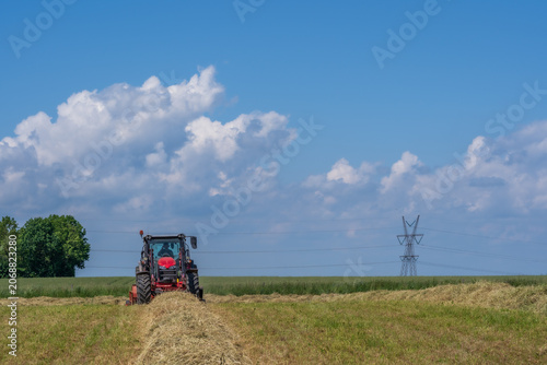 Photos Red tractor raking hay on a sunny summer field