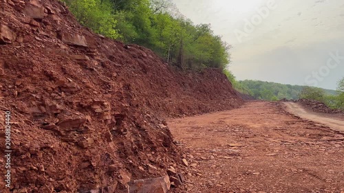 Tracking shot along a hillside construction corridor showing extensive earth cutting exposed rock faces graded terrain and ongoing road widening work through a mountainous landscape