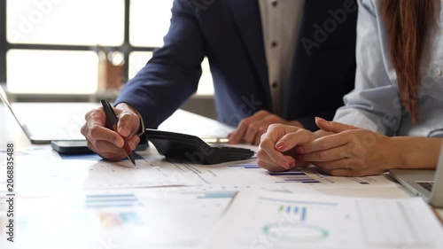 Business colleagues collaborating on a financial report, analyzing marketing data charts, and discussing company investment strategy during a corporate meeting in the office