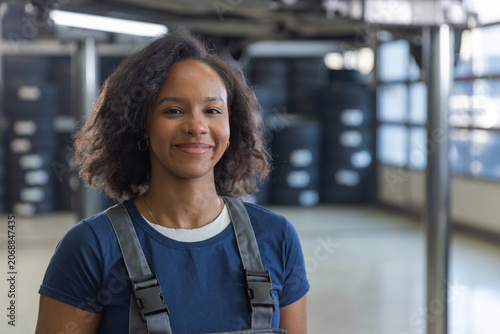 Smiling African American woman, a car mechanic in an auto service repair shop.