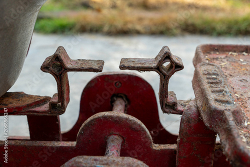 Macro close up shot of a vintage traditional red iron balance scale alignment pointer indicators with weathered rusty texture under natural outdoor daylight, conceptual justice and measure backdrop
