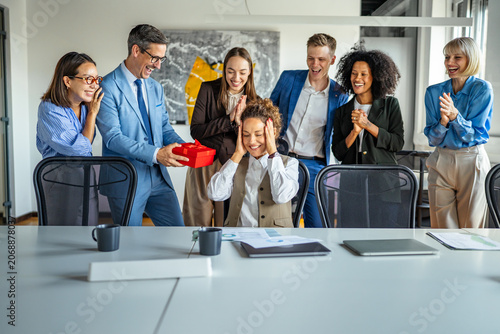 Schilderij op canvas Business colleagues surprising female employee with a gift in office