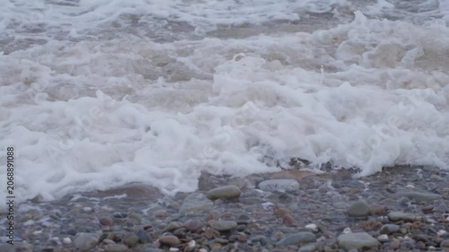 Pebble shore sequence showing surf advancing and retreating over wet rounded stones with low close
