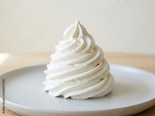 A perfectly swirled, delicate white meringue dessert sits atop a smooth ceramic plate, ready to be savored as a light sweet treat.
