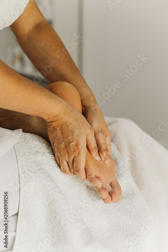 Close up of foot massage therapy session. Female massage therapist's hands.