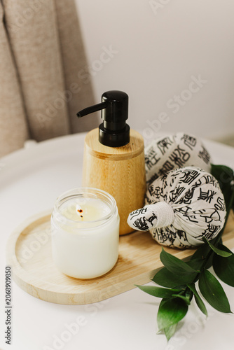 Still life of luxury spa essentials. A bottle with a massage oil and candle on a table.