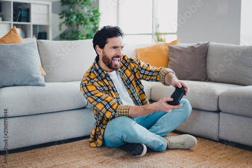 Foto Enthusiastic man playing video games with a controller on the living room floor,