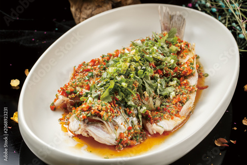 Steamed sea bass with chopped chili peppers served on an oval porcelain plate