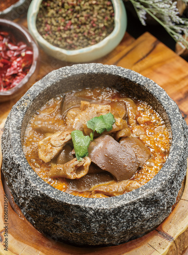 Stone pot of braised pork intestines and blood curd placed on a wooden stand