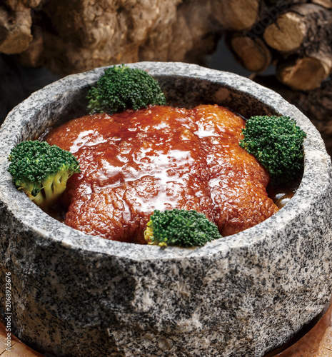 Stone pot of braised pork placed on the tree stump
