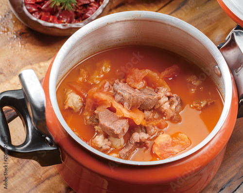 Braised beef brisket with tomatoes in an orange stainless steel pot